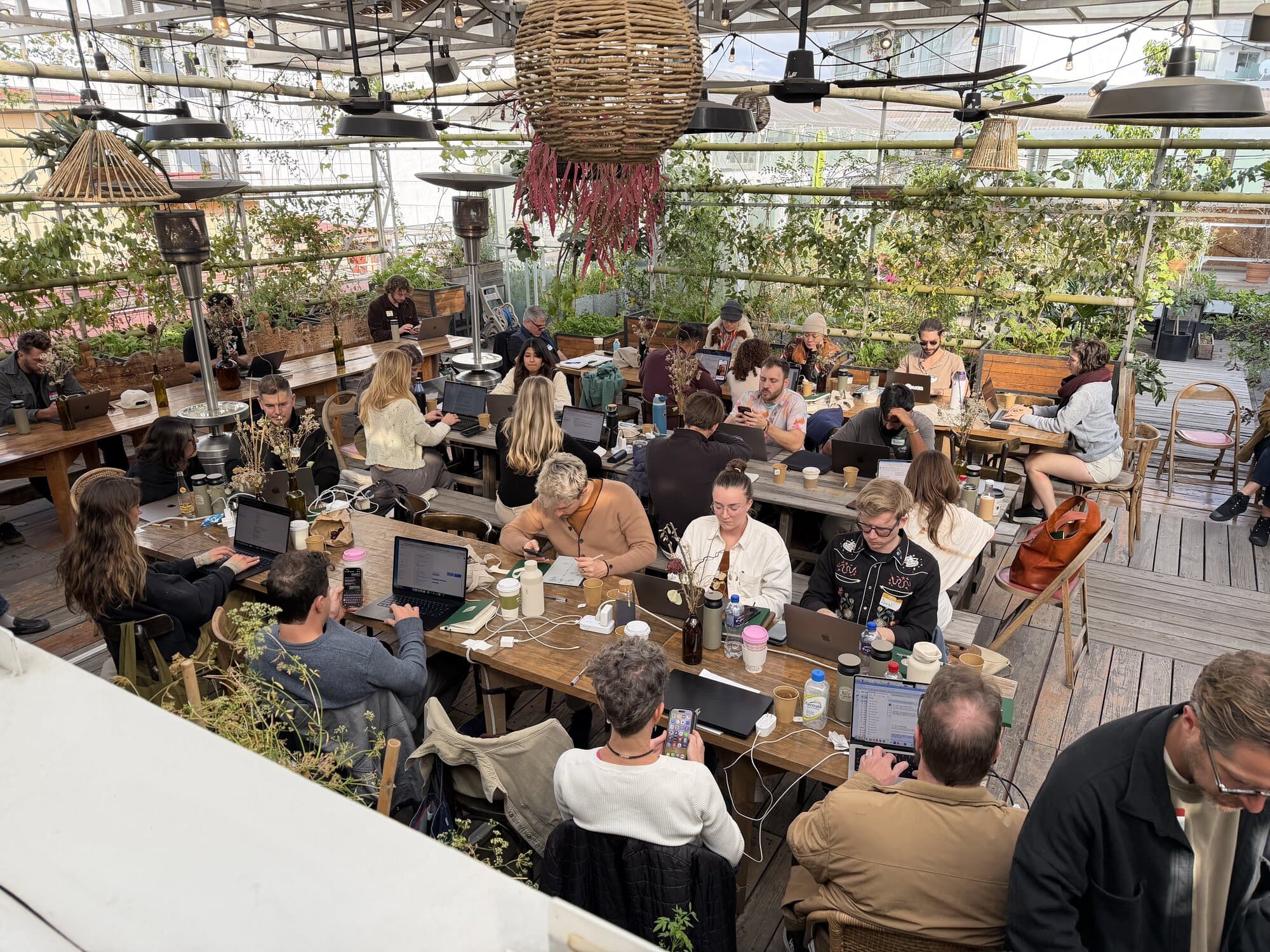 Everyone working at long tables under the greenhouse roof