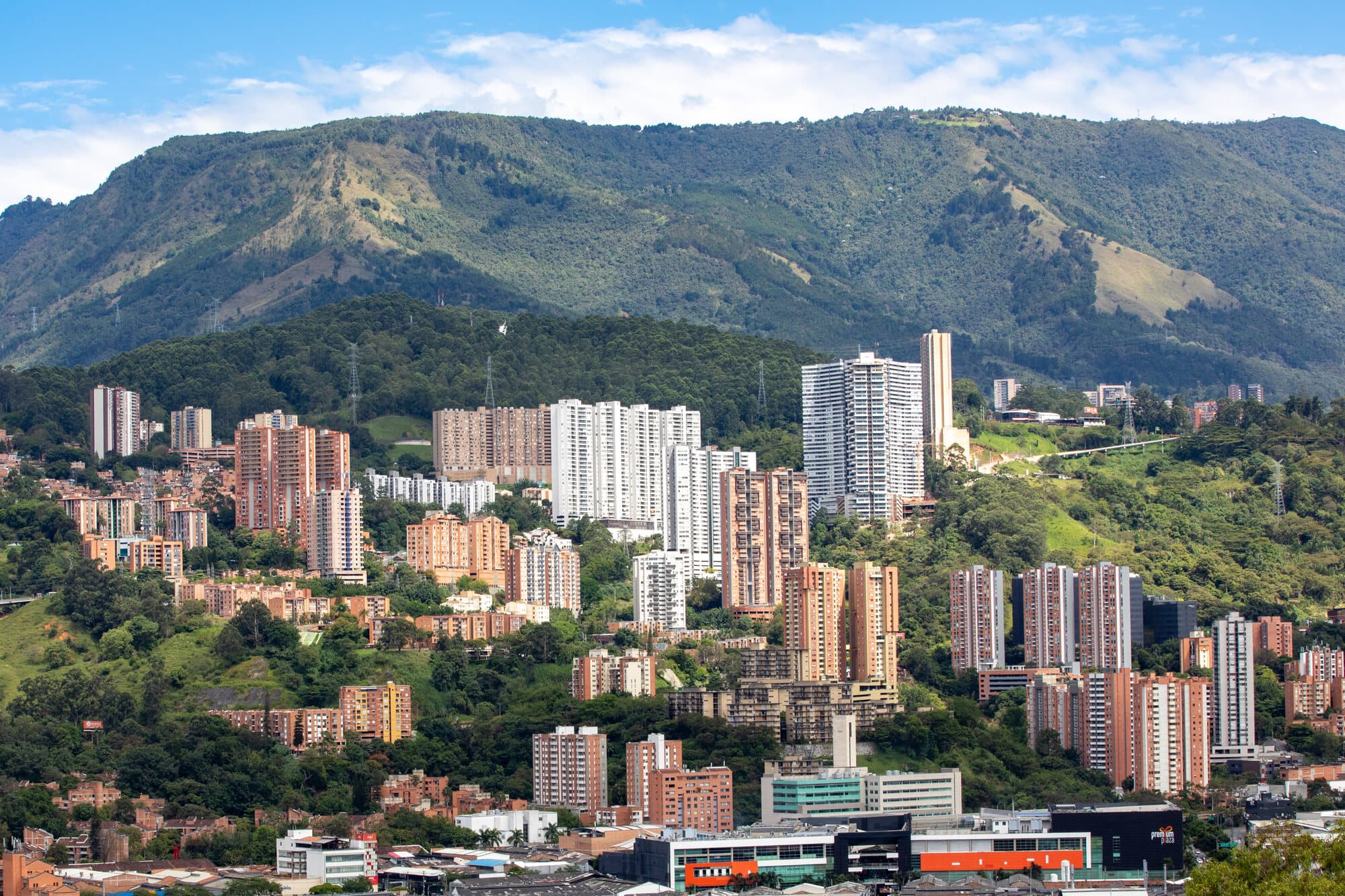 Medellín held in its green valley, the city rising toward forested mountains under a clear sky
