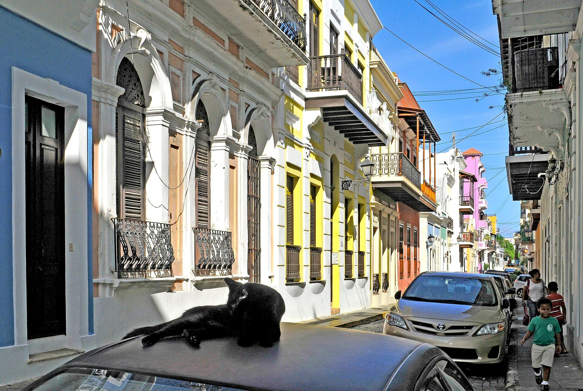 A sunlit street of pastel colonial houses and wrought iron balconies in Old San Juan